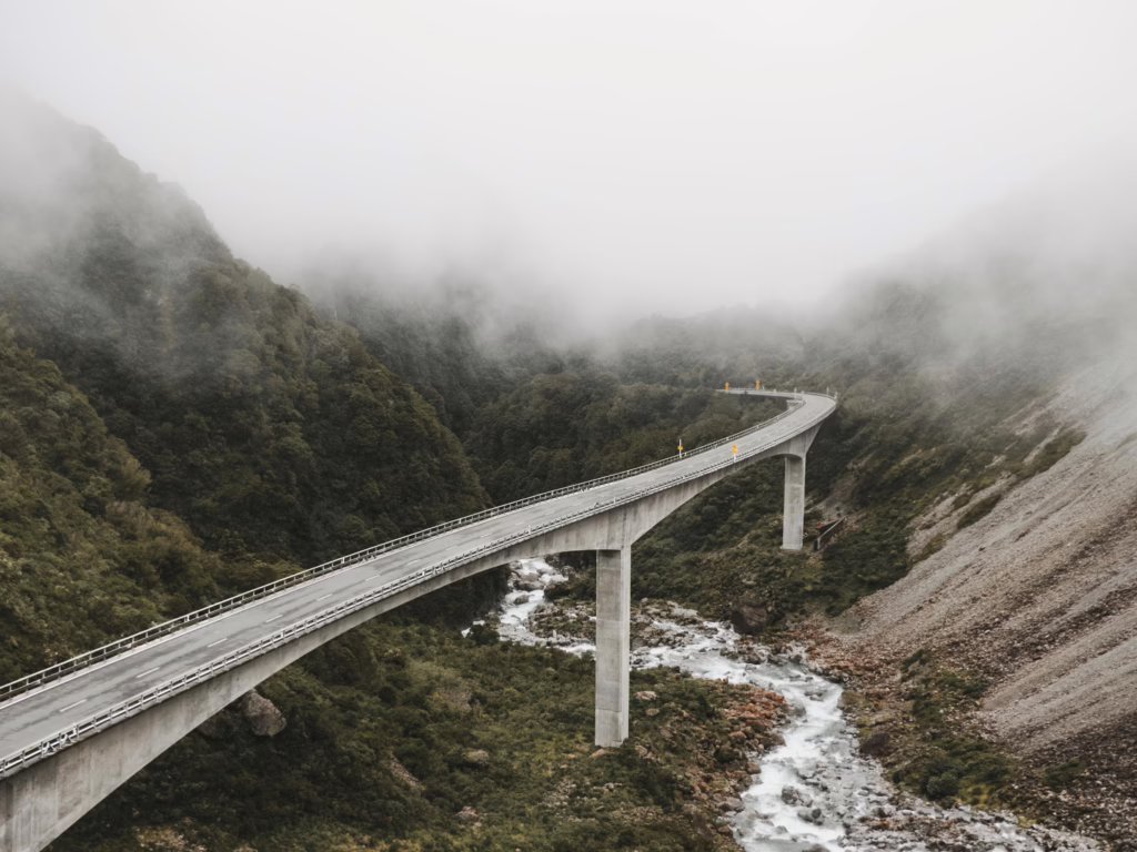 Scenic view of a bridge over a river in a foggy mountain landscape, capturing nature's beauty.